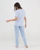 Mujer de espaldas con pijama largo de verano con camiseta celeste de rayas y pantalón liso a juego