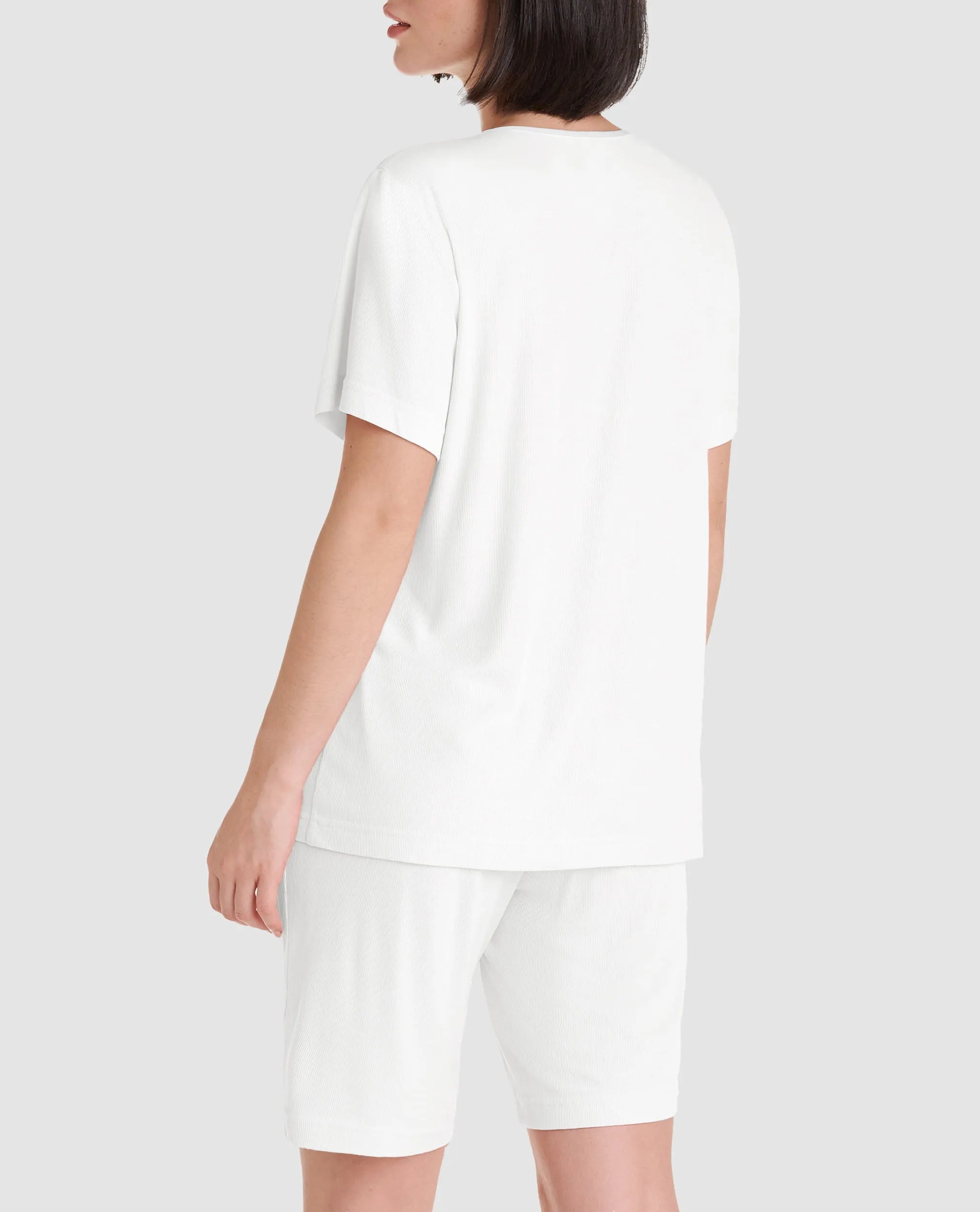 Vista detalle de mujer con camiseta de manga corta a rayas para dormir este verano y cuello con botones rosas