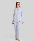 Mujer con pijama azul acero y estampado de hojas blancas. Moda cómoda para dormir y descansar.