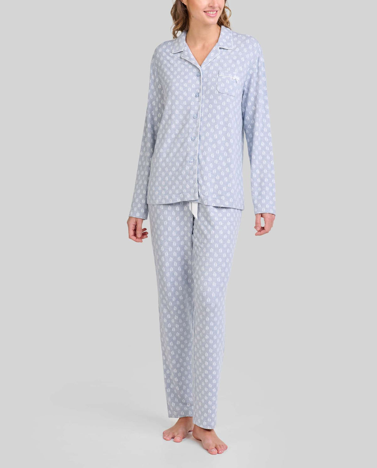 Mujer con pijama azul acero y estampado de hojas blancas. Moda cómoda para dormir y descansar.