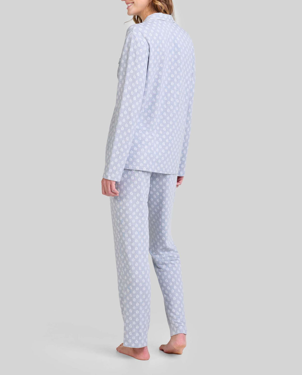 Mujer de espaldas con pijama azul claro de manga larga con estampado hojas blancas, moda cómoda.