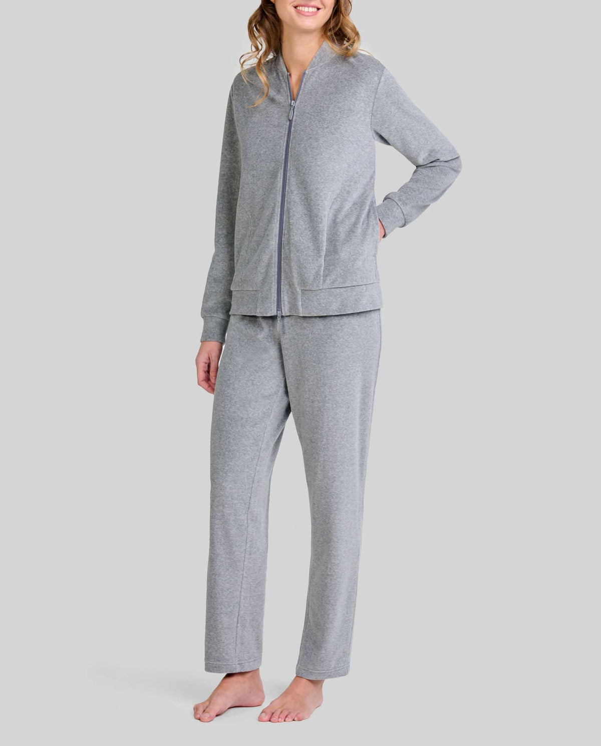 Mujer posando con conjunto de pijama gris chaqueta con cremallera y bolsillos y pantalón a juego.