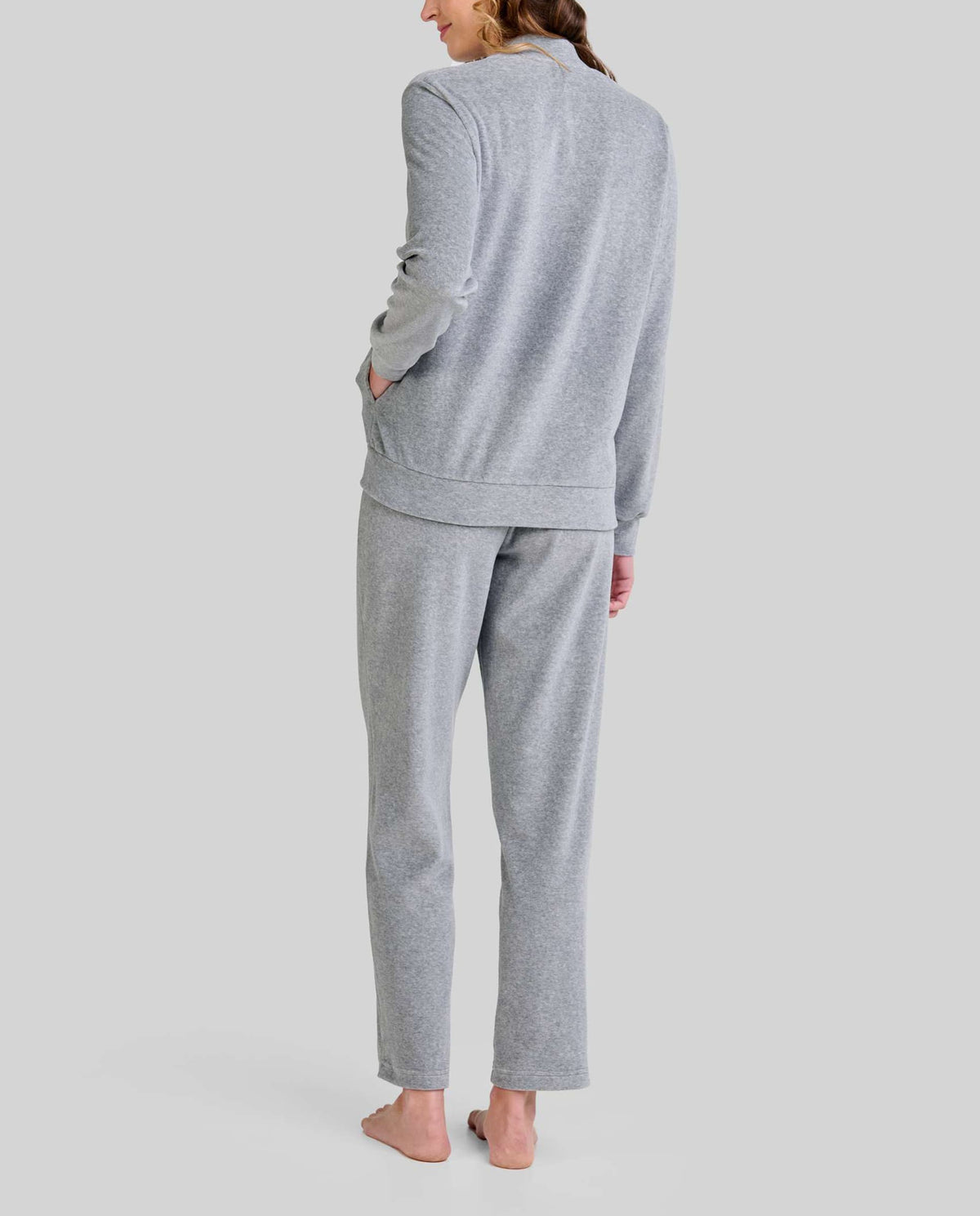 Mujer de espaldas luce pijama largo de cremallera gris claro con bolsillos