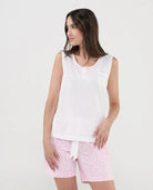 Mujer con pijama corto de verano sin mangas, camiseta blanca punto flamé y pantalón rosa con florecitas blancas