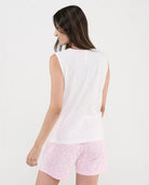 Mujer de espaldas con pijama de verano corto top blanco sin mangas y pantalón rosa de florecitas
