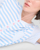 Vista detalle de mujer con camiseta de manga corta a rayas para dormir este verano y cuello con botones rosas
