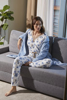 Mujer con pijama floral y bata azul sentada en sofá gris