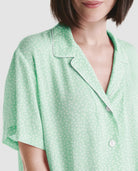Mujer luce chaquetilla de pijama largo abierta con botones en raso marfil jacquard