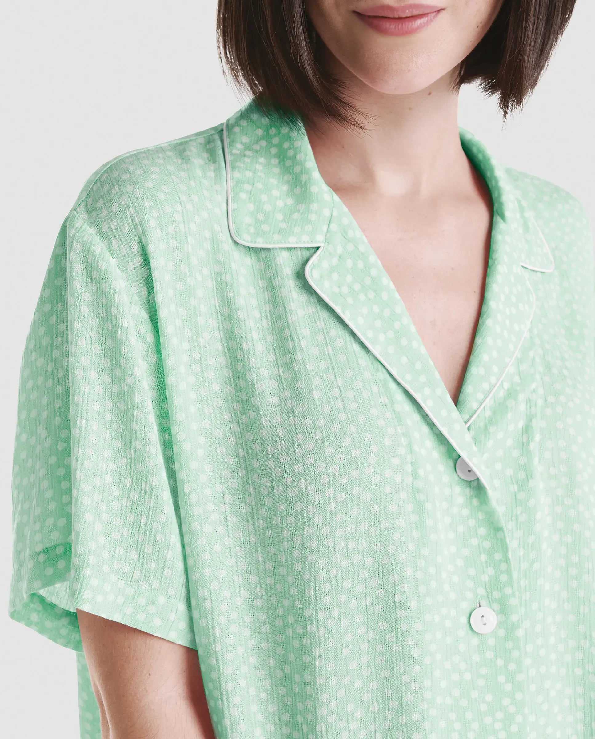 Mujer luce chaquetilla de pijama largo abierta con botones en raso marfil jacquard