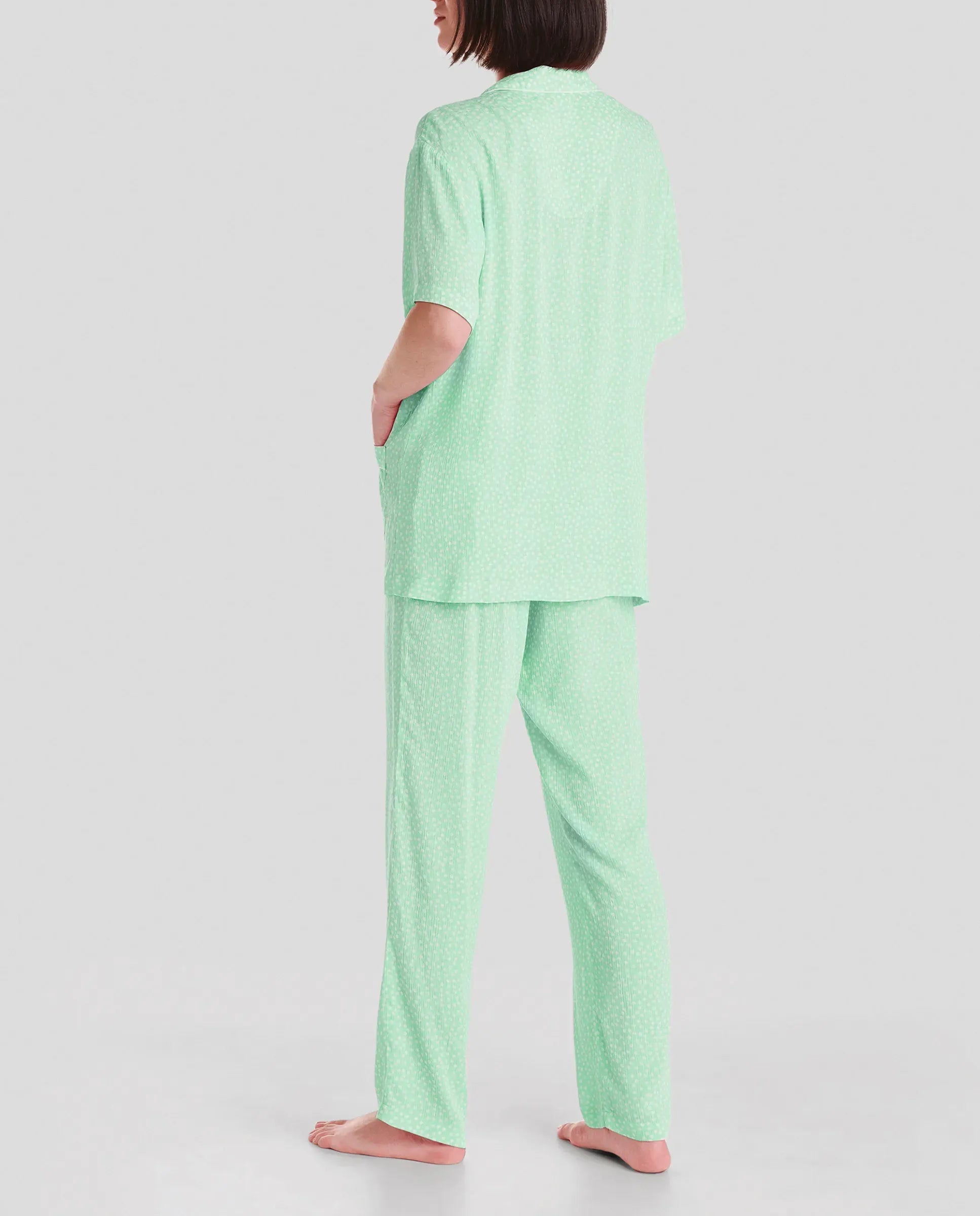 Modelo posa con pijama de verano gris con pantalón largo y camiseta manga corta estampado plumas
