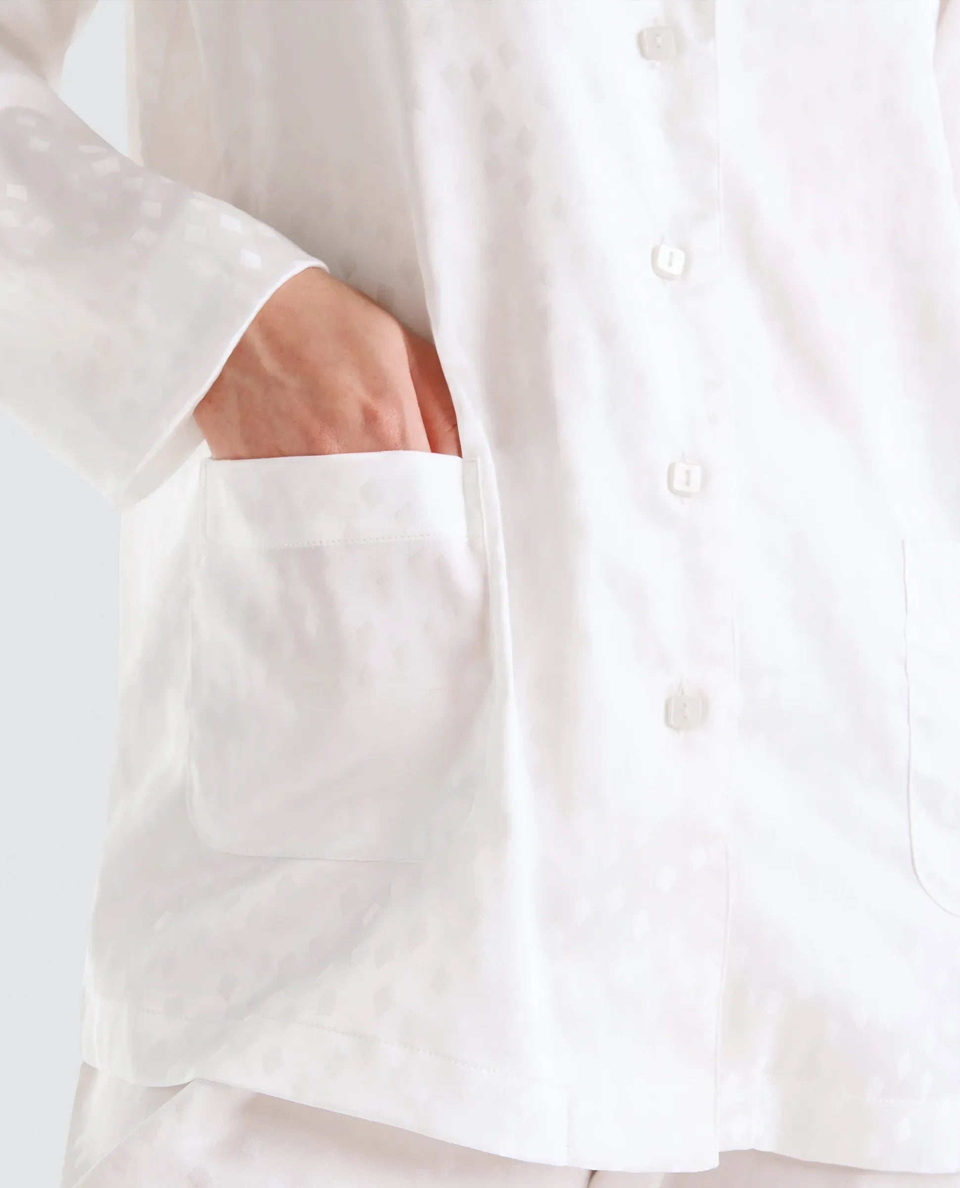 Vista detalle de chaqueta de pijama de verano de raso abierta con botones y bolsillos de plastón