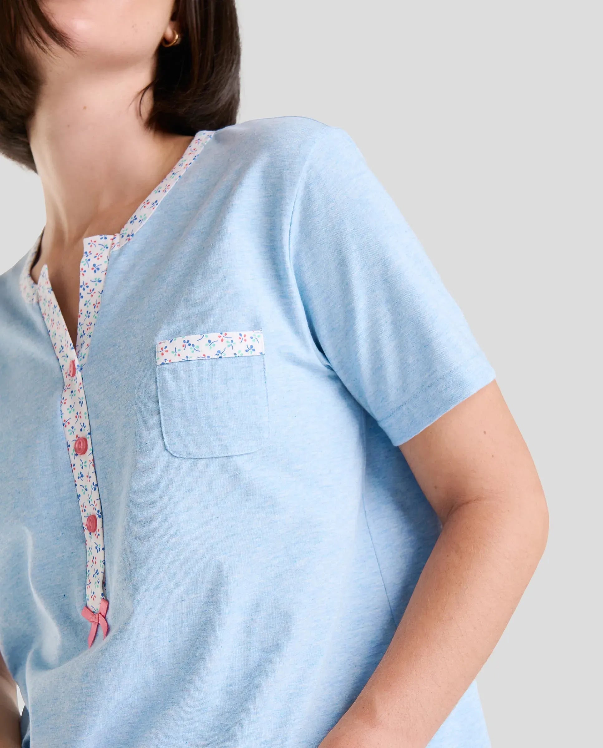 Detalle de cuello abierto con pata de florecitas y botones de pijama de manga corta celeste
