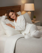 Mujer descansa con pijama largo marfil de estampado jacquard, chaqueta abierta con botones, bolsillos y pantalón largo.