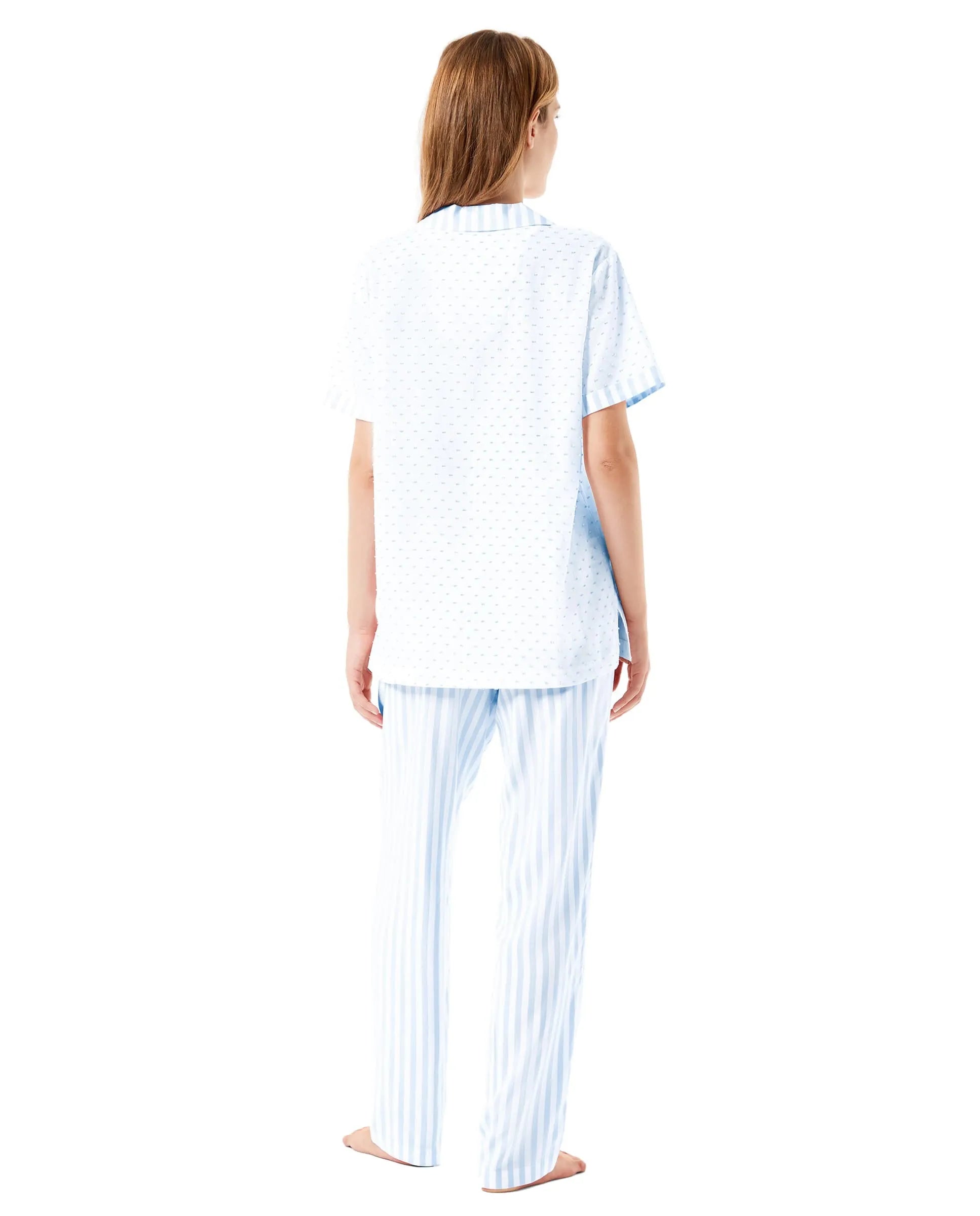 Mujer descansa con pijama largo marfil de estampado jacquard, chaqueta abierta con botones, bolsillos y pantalón largo.