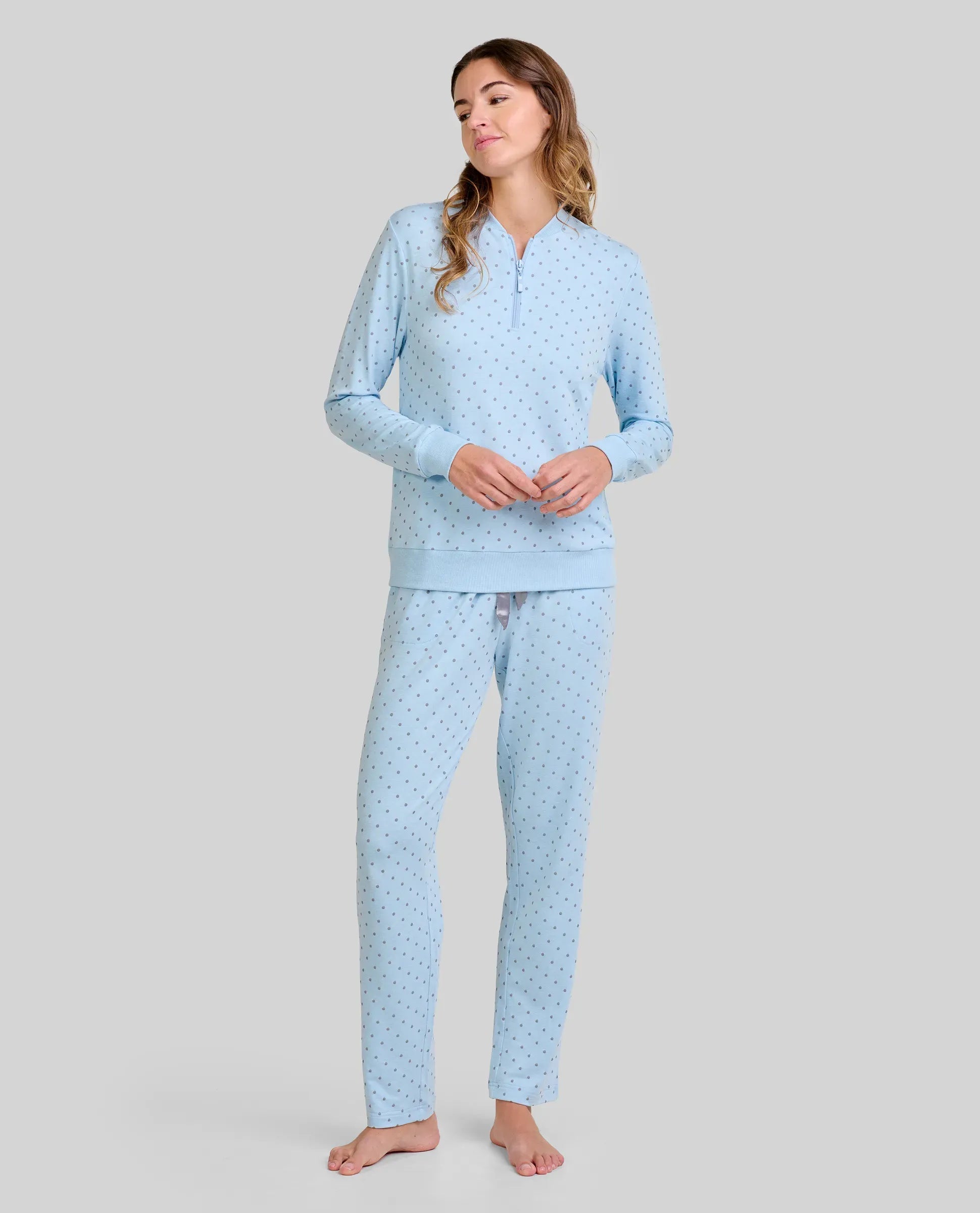 Mujer con cálido pijama largo celeste en tejido vigoré con estampado de pequeños topos grises