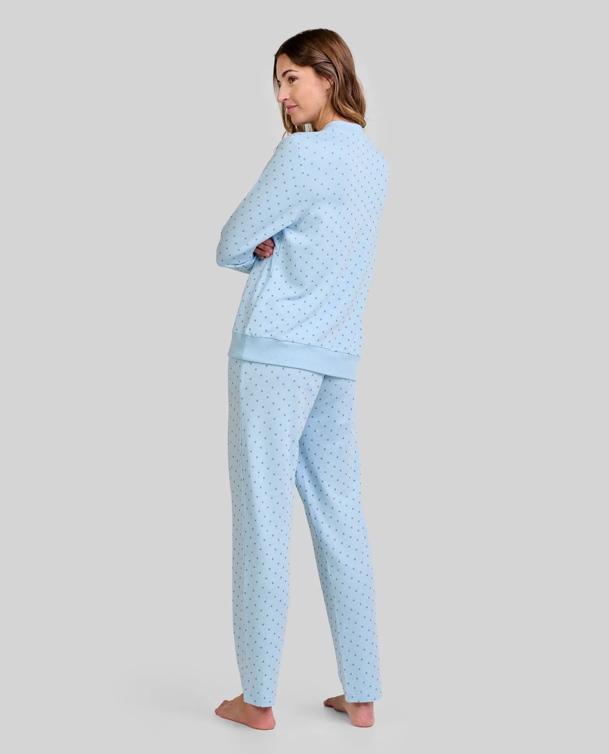 Mujer de espaldas luce cómoda y moderno pijama celeste con pequeños topos grises