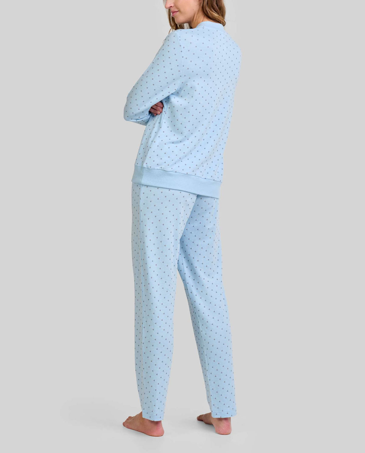 Mujer de espaldas luce cómoda y moderno pijama celeste con pequeños topos grises