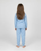 Niña de espaldas con cómodo y calentito pijama de invierno azul claro con topitos grises