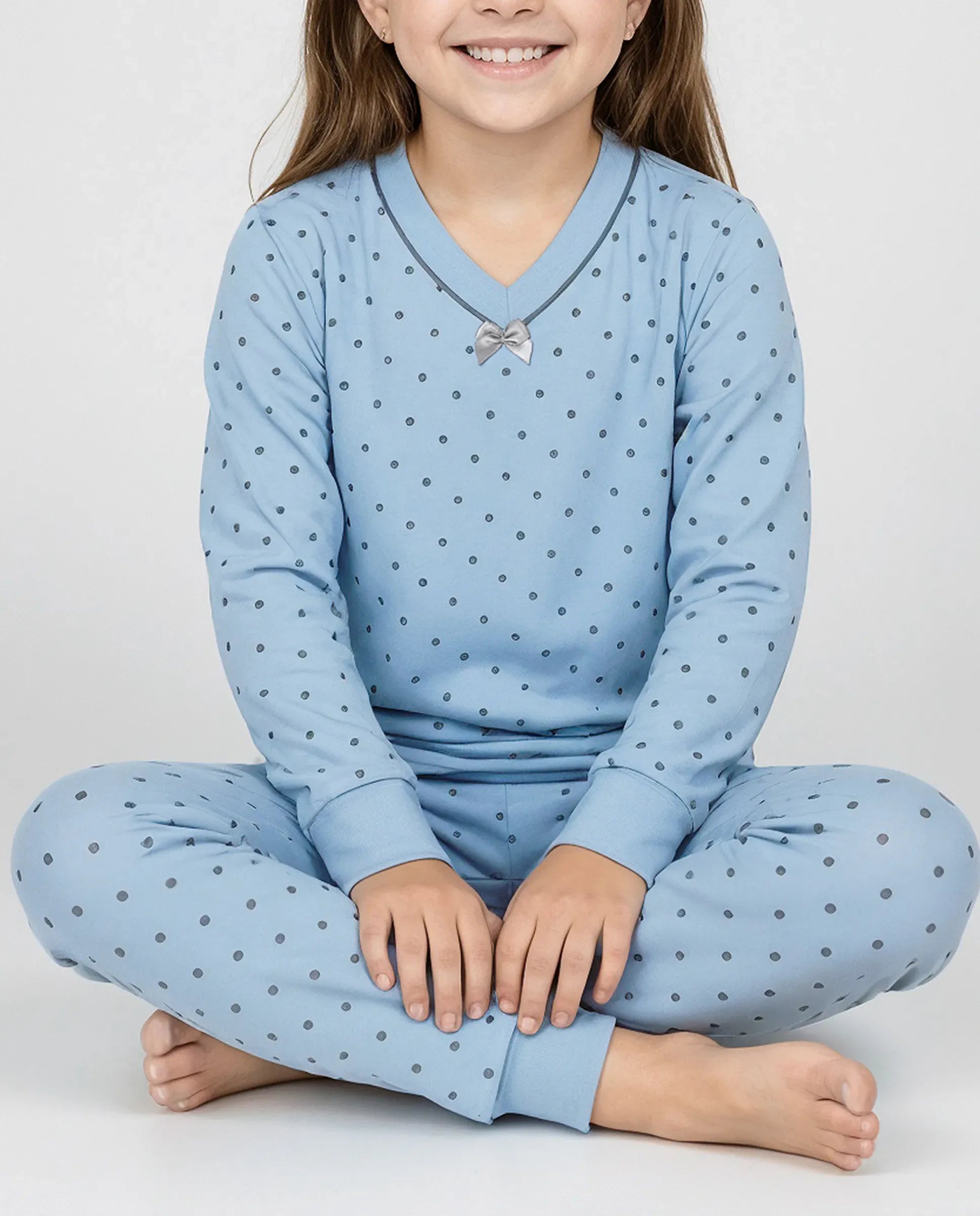 Detalle del confortable pijama de invierno para niña azul a topitos con cuello en pico y lazo decorativo