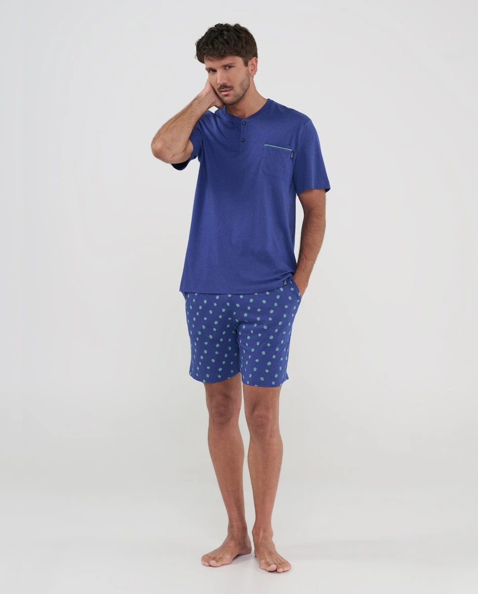 hombre posa con pijama corto veraniego de color azul con pantalón corto de tortuguitas y bolsillos