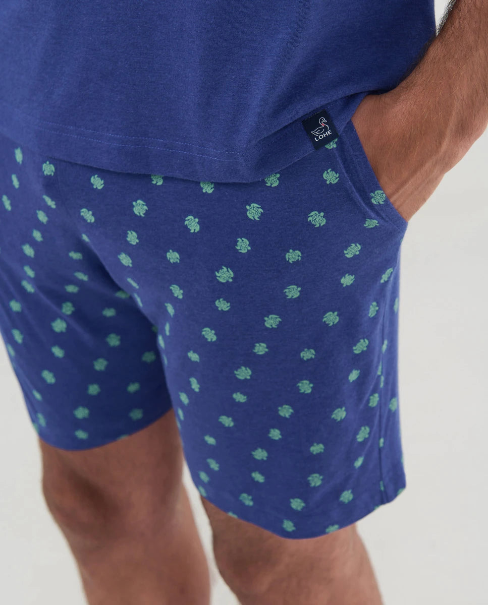 Detalle de pantalón de pijama azul con pequeñas tortugas verdes y bolsillos laterales