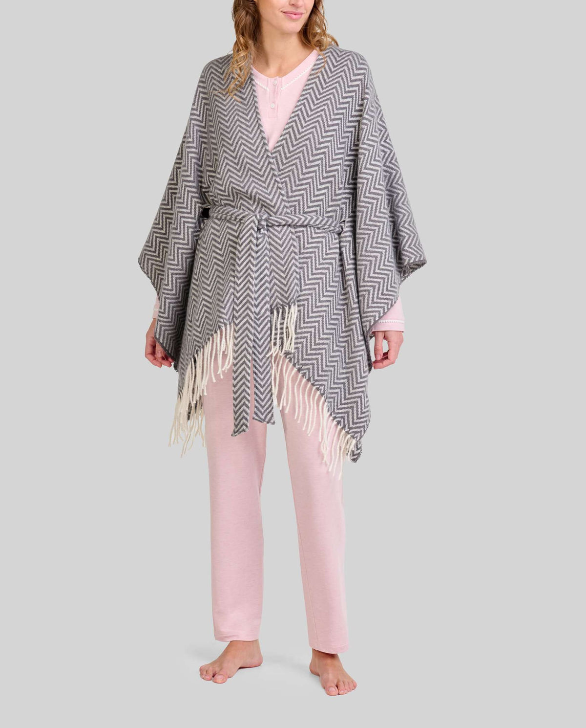 Mujer con pijama rosa claro y poncho  gris con flecos y cinturón