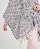 Mujer luciendo un poncho gris y blanco de espiga con flecos y cinturón para invierno