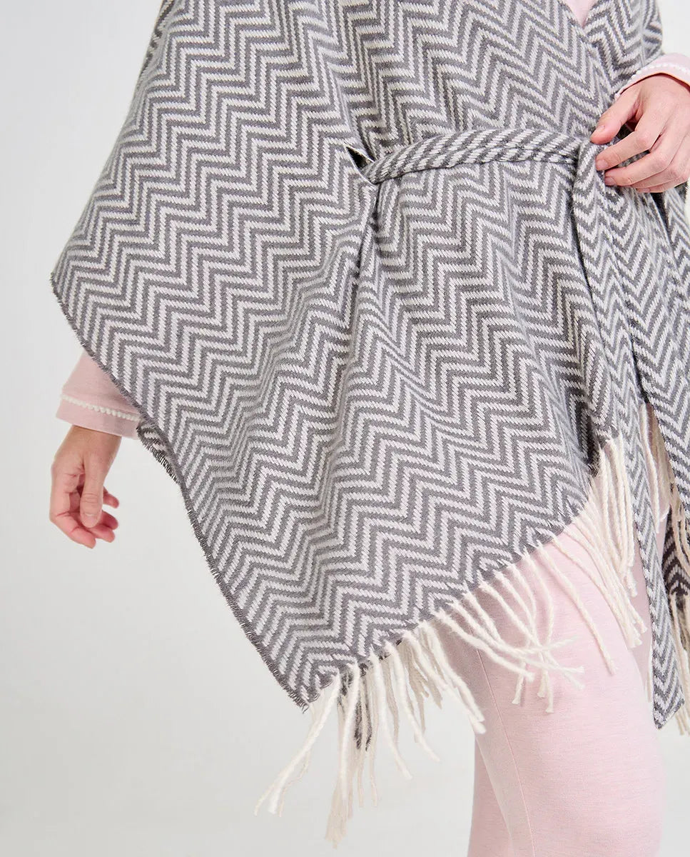Mujer luciendo un poncho gris y blanco de espiga con flecos y cinturón para invierno