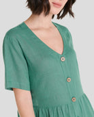 Detalle del escote en pico sin cuello, abotonado del vestido corto de lino verde de verano marca LOHE