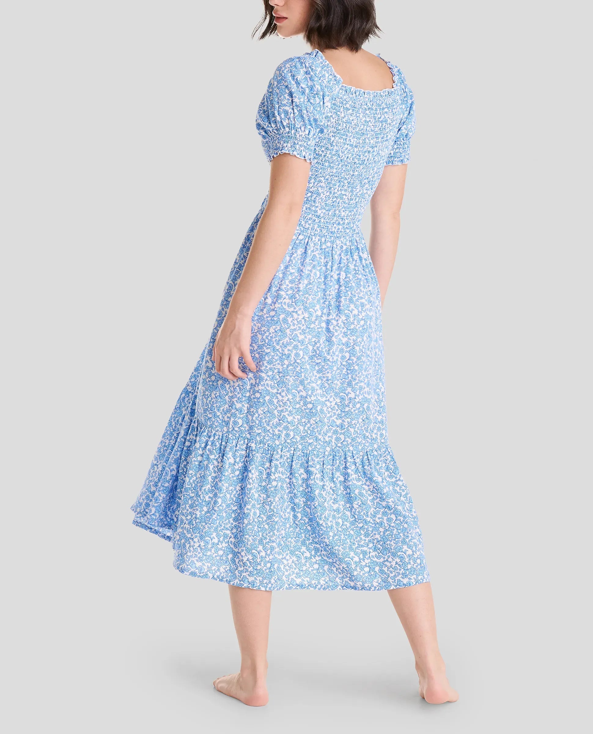 Vista trasera de mujer con vestido de verano hasta la rodilla estampado azul de flores y manga corta