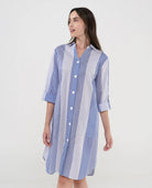 Mujer luce vestido camisero midi a rayas azules y blancas con botones blancos y mangas tres cuartos.
