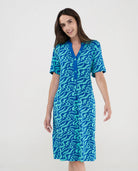 Mujer luce vestido veraniego corto de manga corta estampado azul ondas y cuello con botones