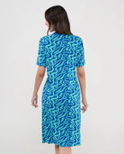Vista de espaldas de mujer con vestido playero de manga corta azul estampado ondas