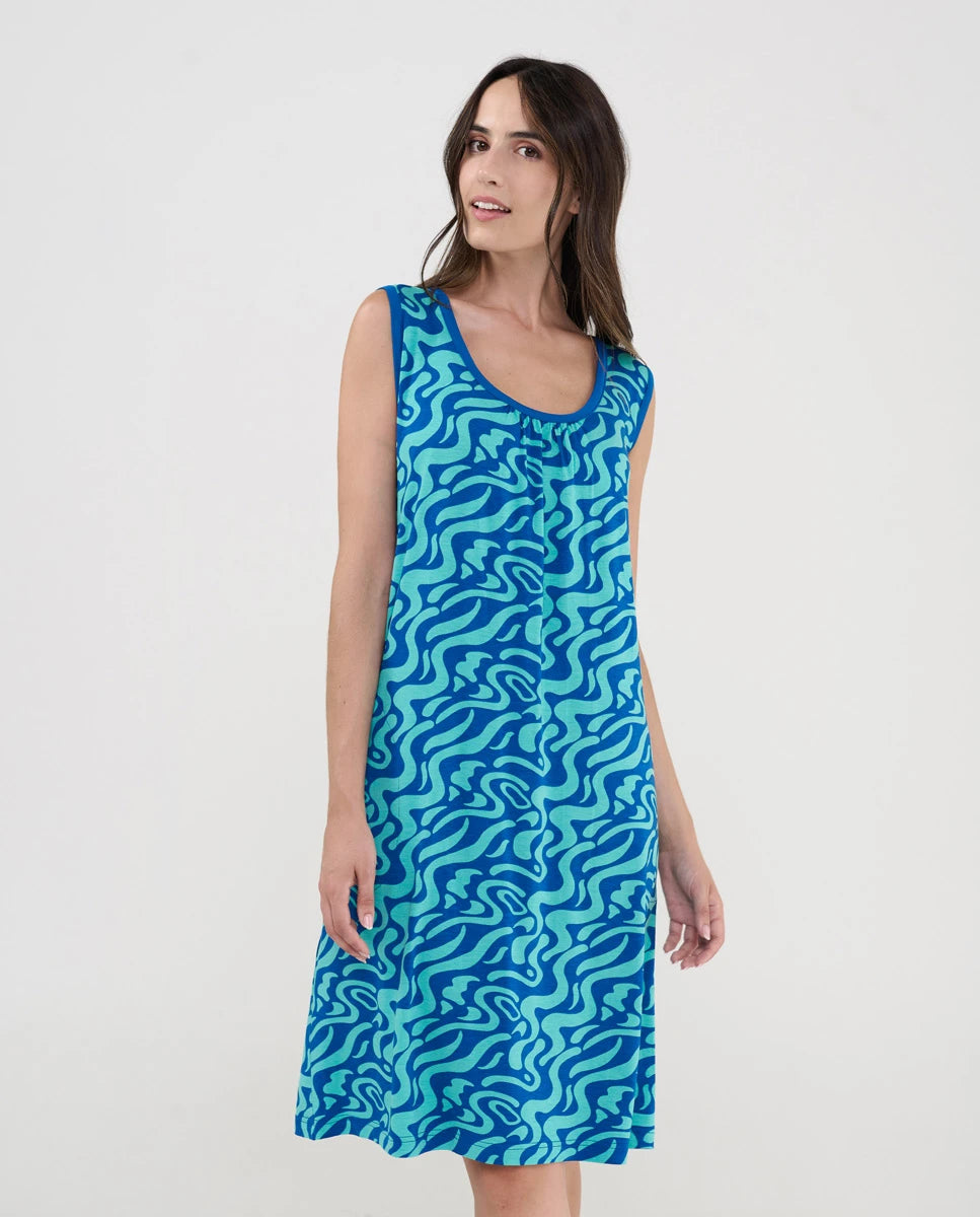 Mujer con vestido playero corto sin mangas en punto azul estampado ondas con cuello redondo y boslillos