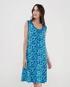 Mujer con vestido playero corto sin mangas en punto azul estampado ondas con cuello redondo y boslillos