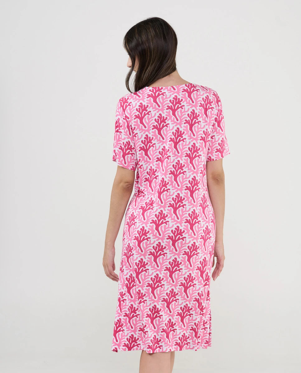 Mujer de espaldas luce cómodo vestido playero estampado fucsia