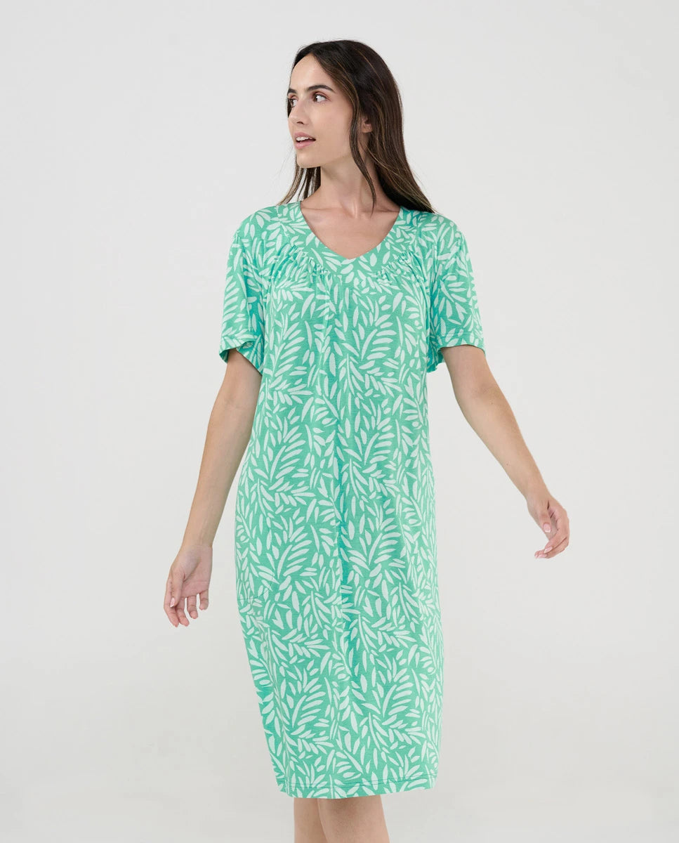 Mujer posando con vestido de baño verde de manga corta y estampado de hojas.