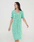 Mujer posando con vestido de baño verde de manga corta y estampado de hojas.