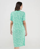 Mujer con vestido de verano corto verde con estampado de hojas vista de espaldas