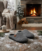 Pantuflas grises sobre suelo de madera en salón navideño